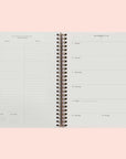 A spiral bound planner and a look at the interior that features a monthly and weekly view.