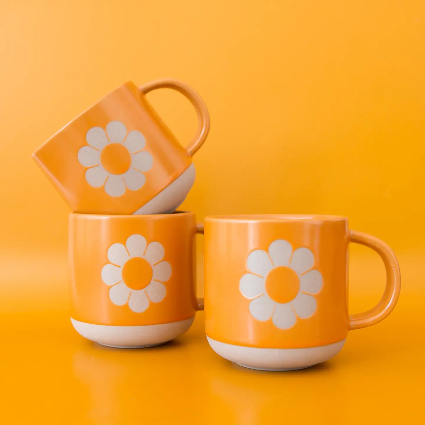 A yellow ceramic mug with a flower shape in the center. 