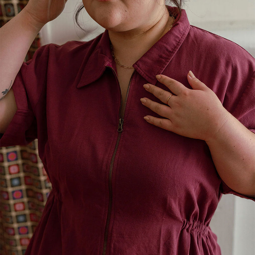 a woman wearing a burgundy colored utility mini dress