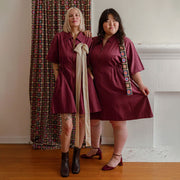 two women wearing a burgundy colored utility mini dress