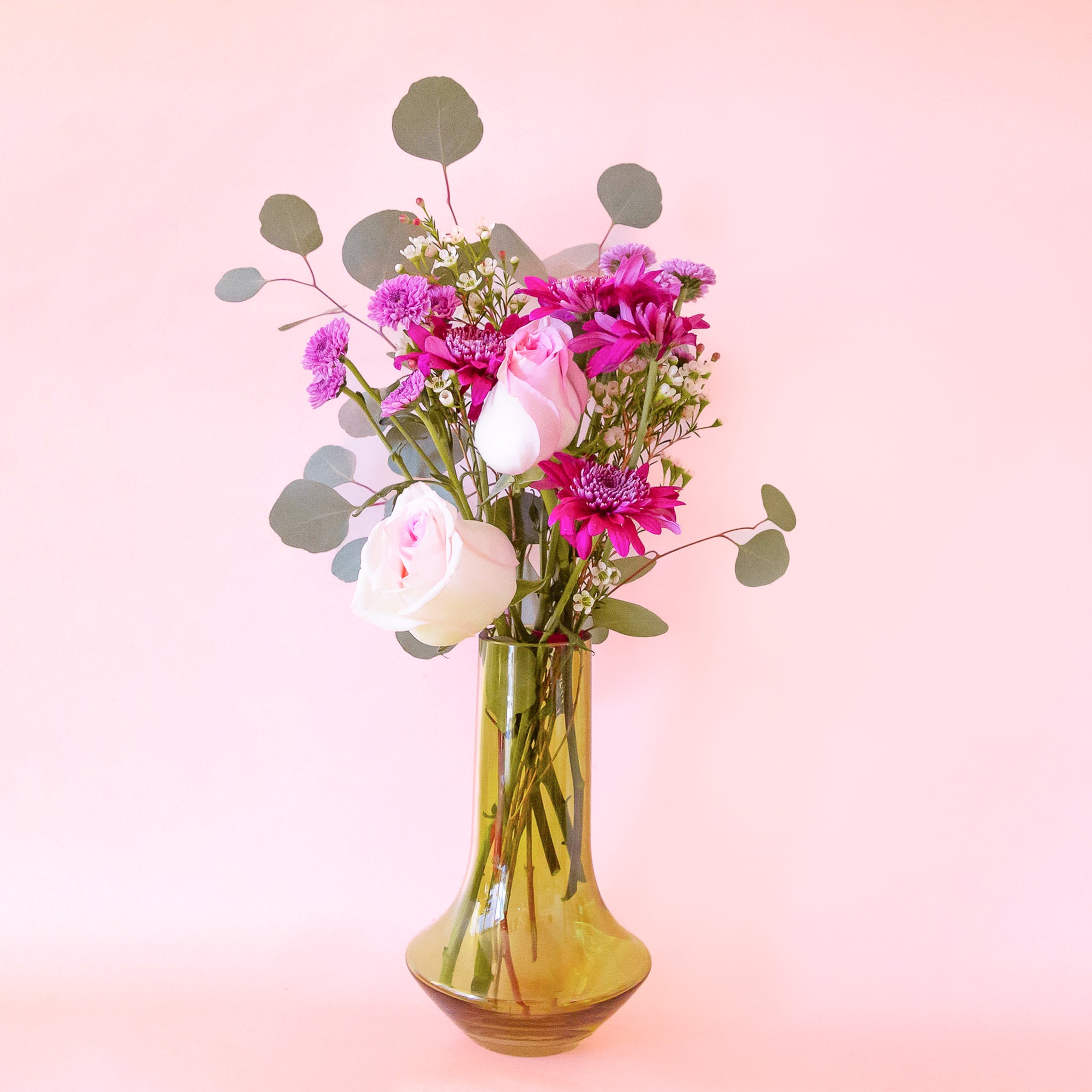 A glass green vase with a bottle neck and wide base. 