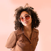 A creamy white pair of round oversized sunglasses with a light brown / pink lens.