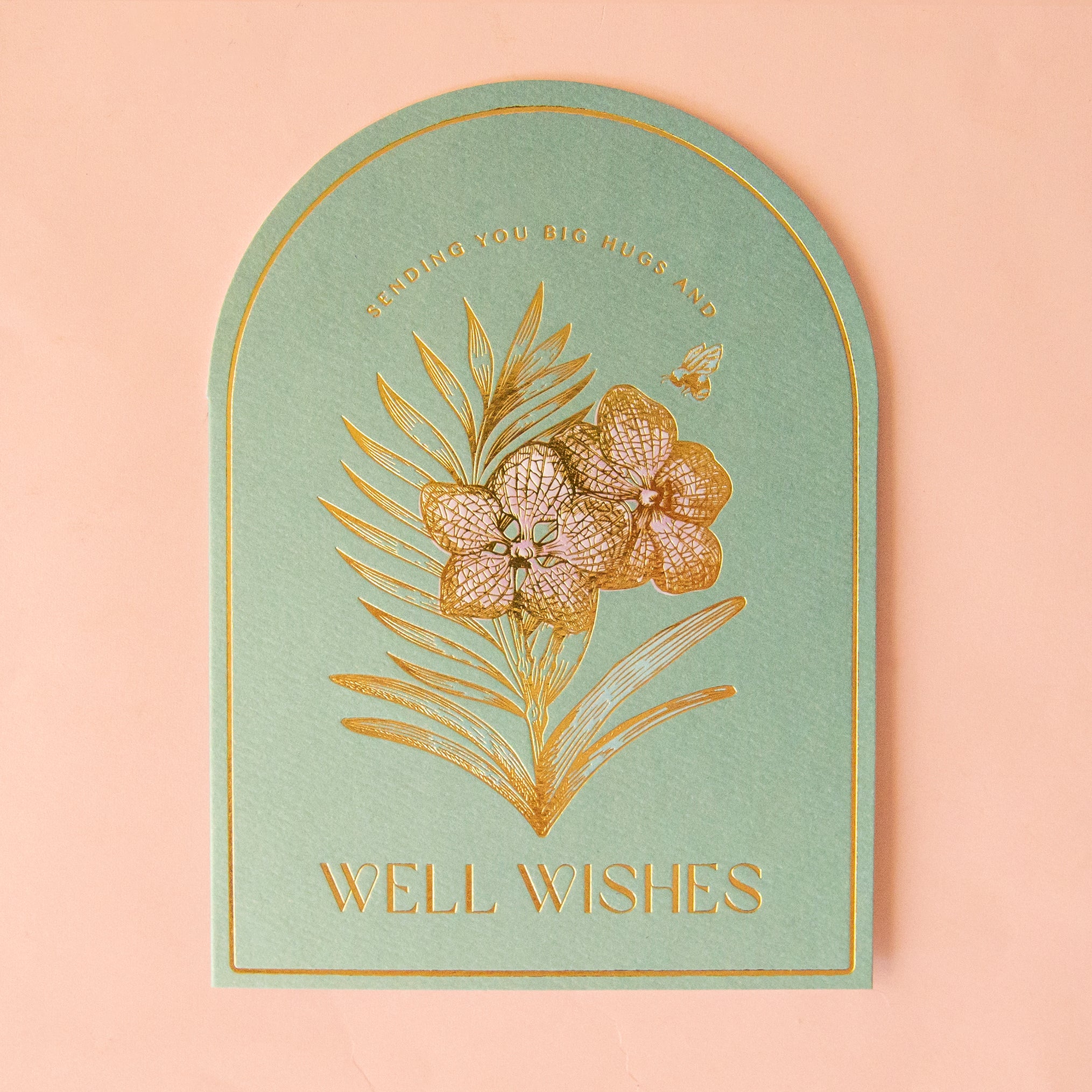 On a tan background is a light green card with an orchid in gold foil and text above and below that reads, "Sending you big hugs and well wishes". 