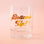 A clear glass tumbler with gold text that reads, 'Bottoms Up!'. 