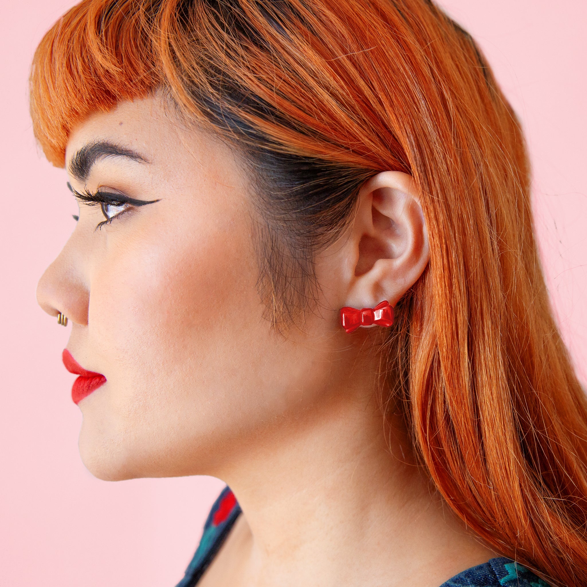 A model wearing red bow shaped earrings. 