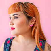 A girl wearing pink bow earrings.