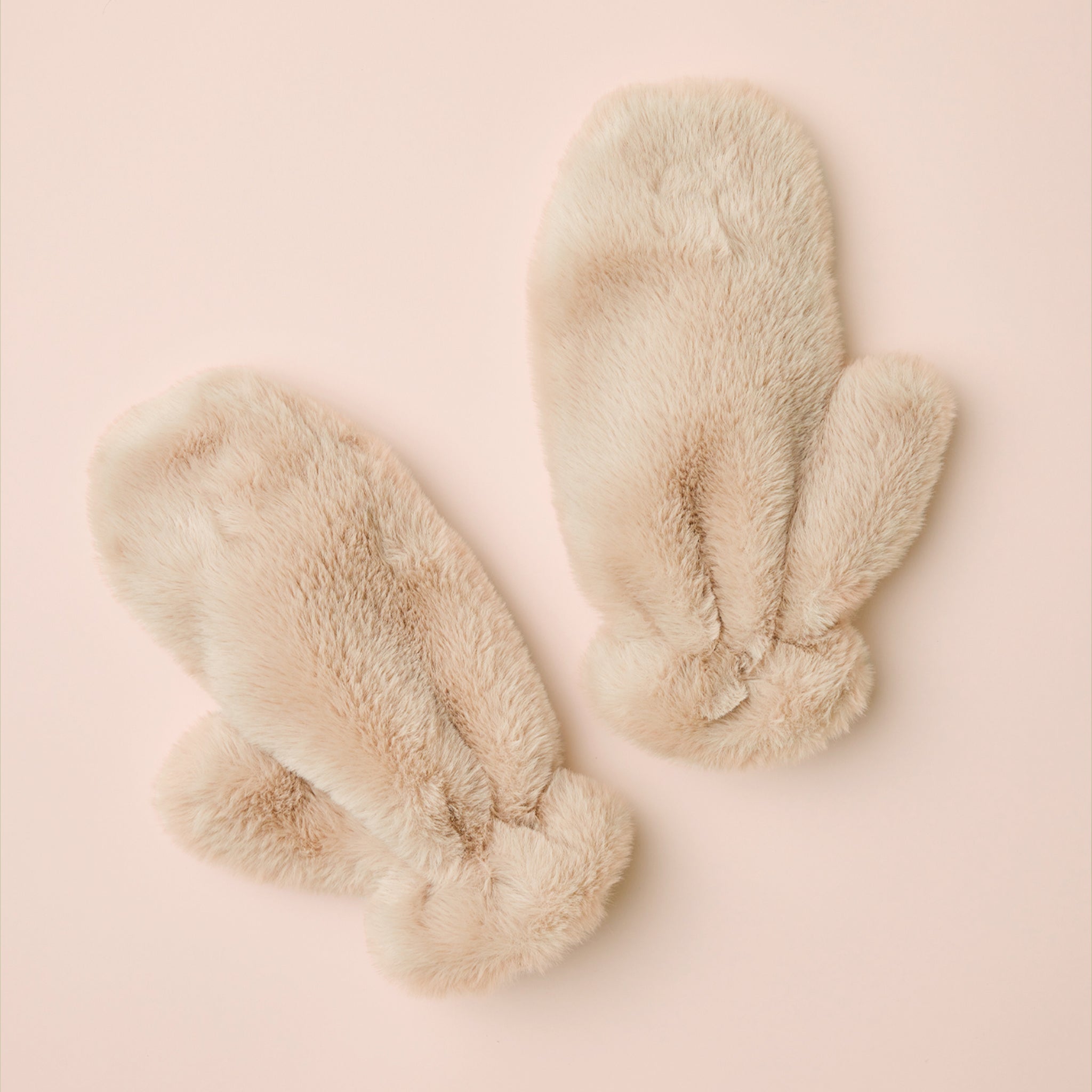 Oatmeal colored faux fur mittens shown against a neutral background. 