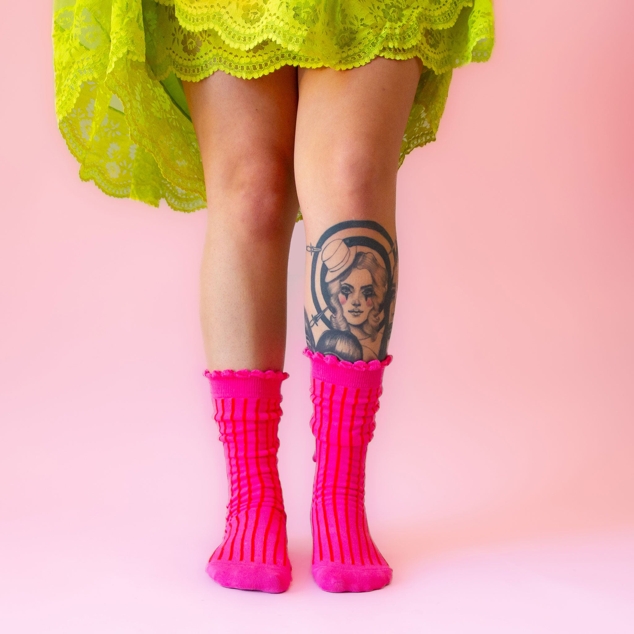 A pair of fuchsia colored striped socks with a ruffle detail at the top. 