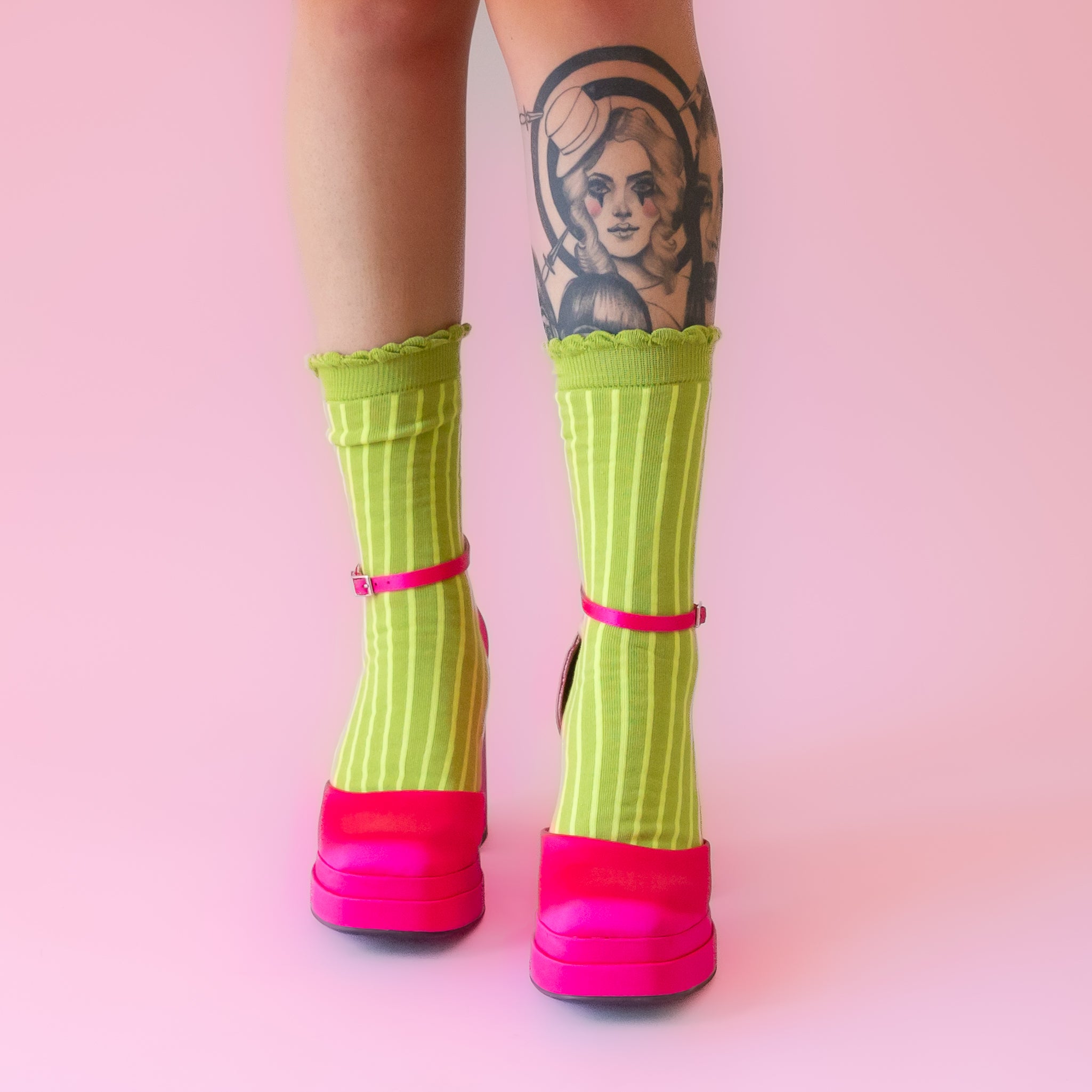 A model wearing a pear of lime green striped socks with a ruffle detail at the top. 