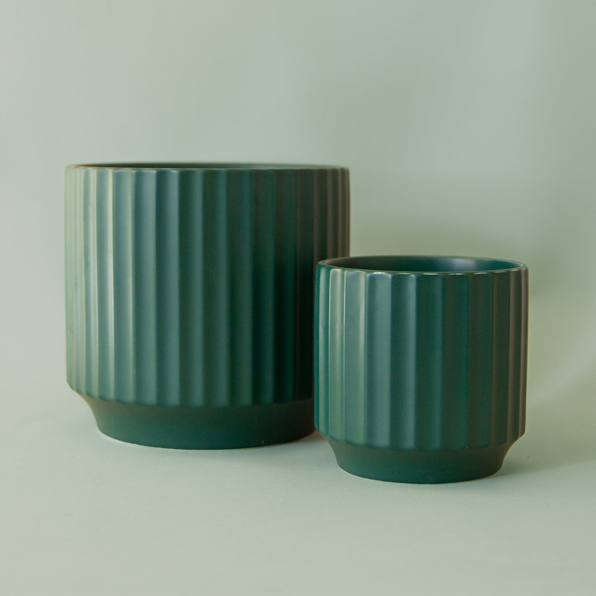 A dark green fluted ceramic planter in two different sizes. 
