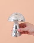 On a peach background is a disco mushrooms with mirrored square pieces all over.