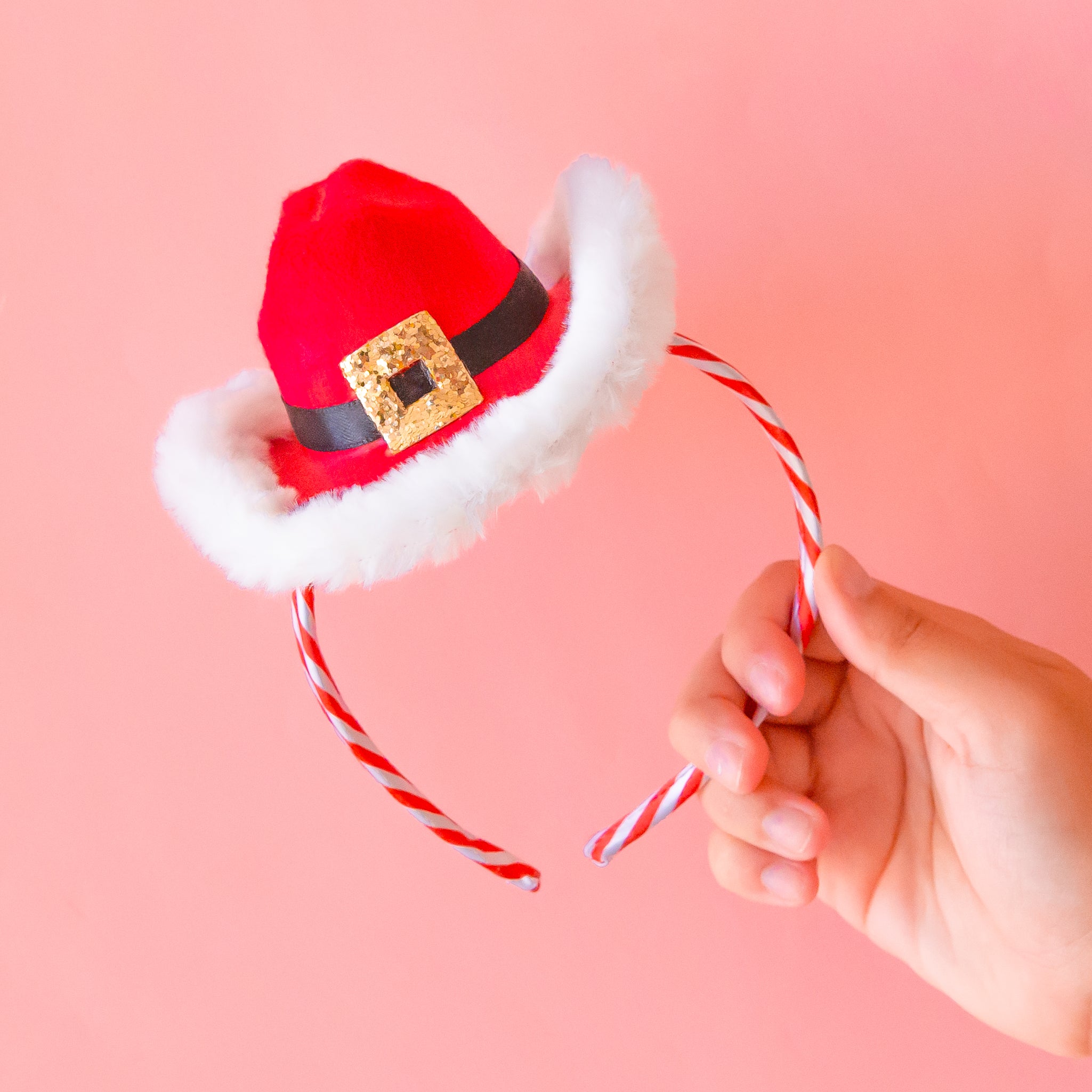 A red and white headband with a red cowboy hat shaped &quot;Santa&quot; inspired hat on top of it. 