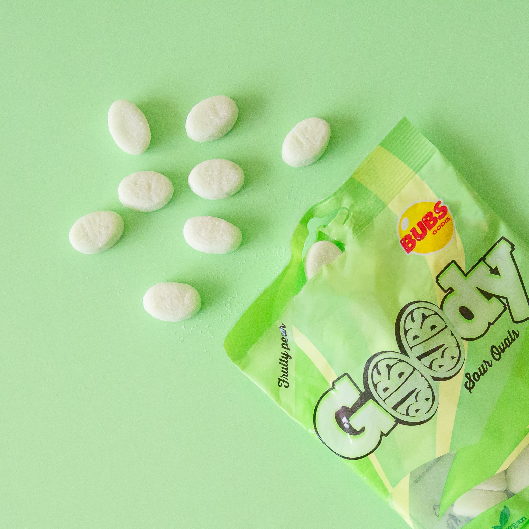 On a lime green ground is an image of white candies spilling out of a green bag that reads &quot;Goody sour ovals&quot;.  The candy says &quot;fruity pear&quot; flavor.