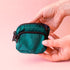 A cypress green colored fanny pack bag charm with black zippers and details. 