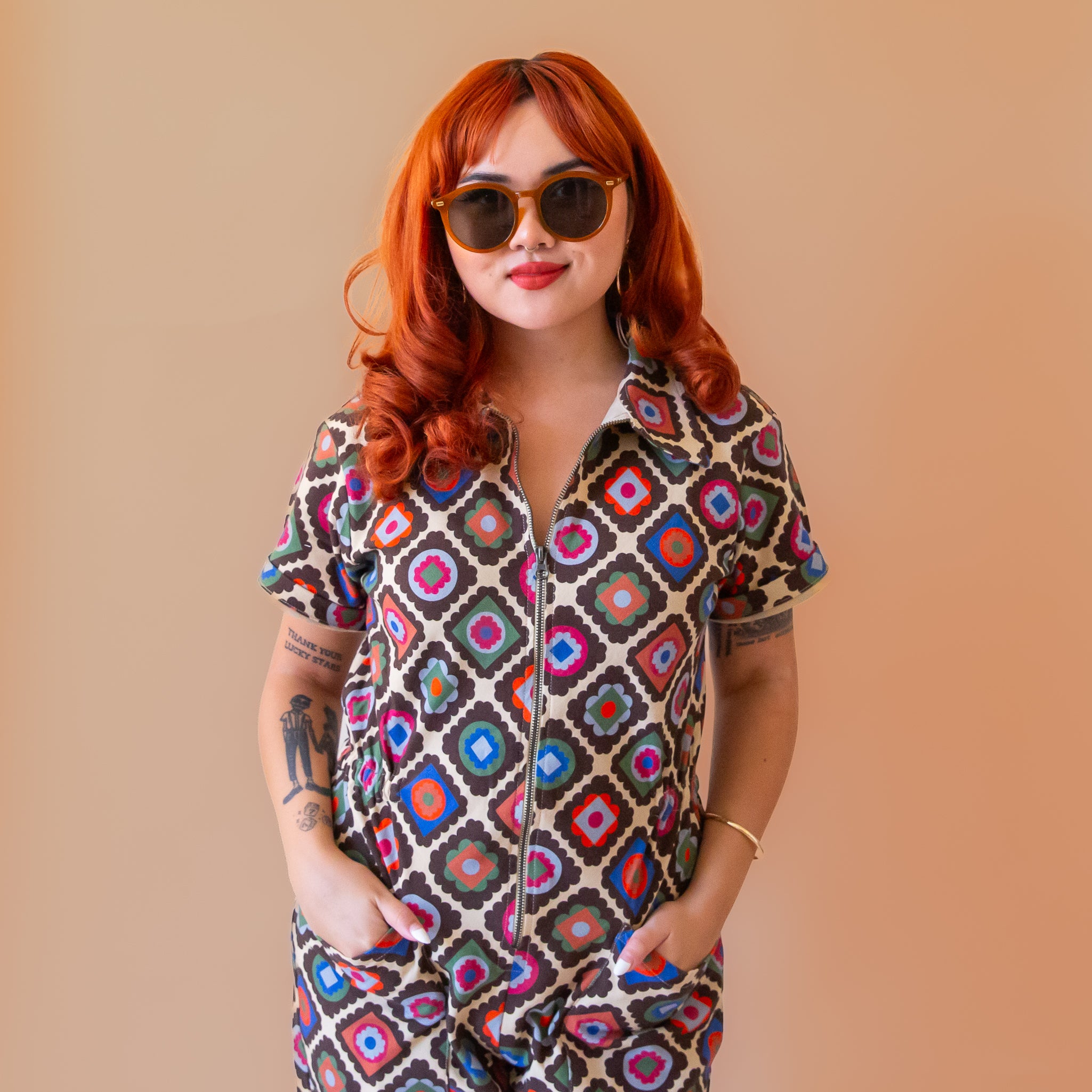 A multi-colored short sleeve jumpsuit with a zipper up the front and a floral pattern. 