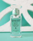 A box of perfume and a clear bottle with a teal blue label on the front that reads, "After Sun Scent of the Illustrious".