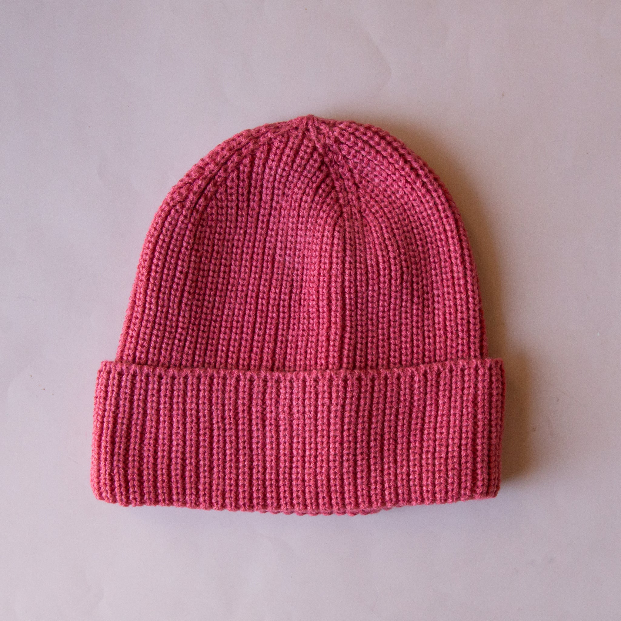 A knit beanie in a berry pink color. 