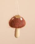 A cocoa colored mushroom ornament with white spots and a light wood stem.