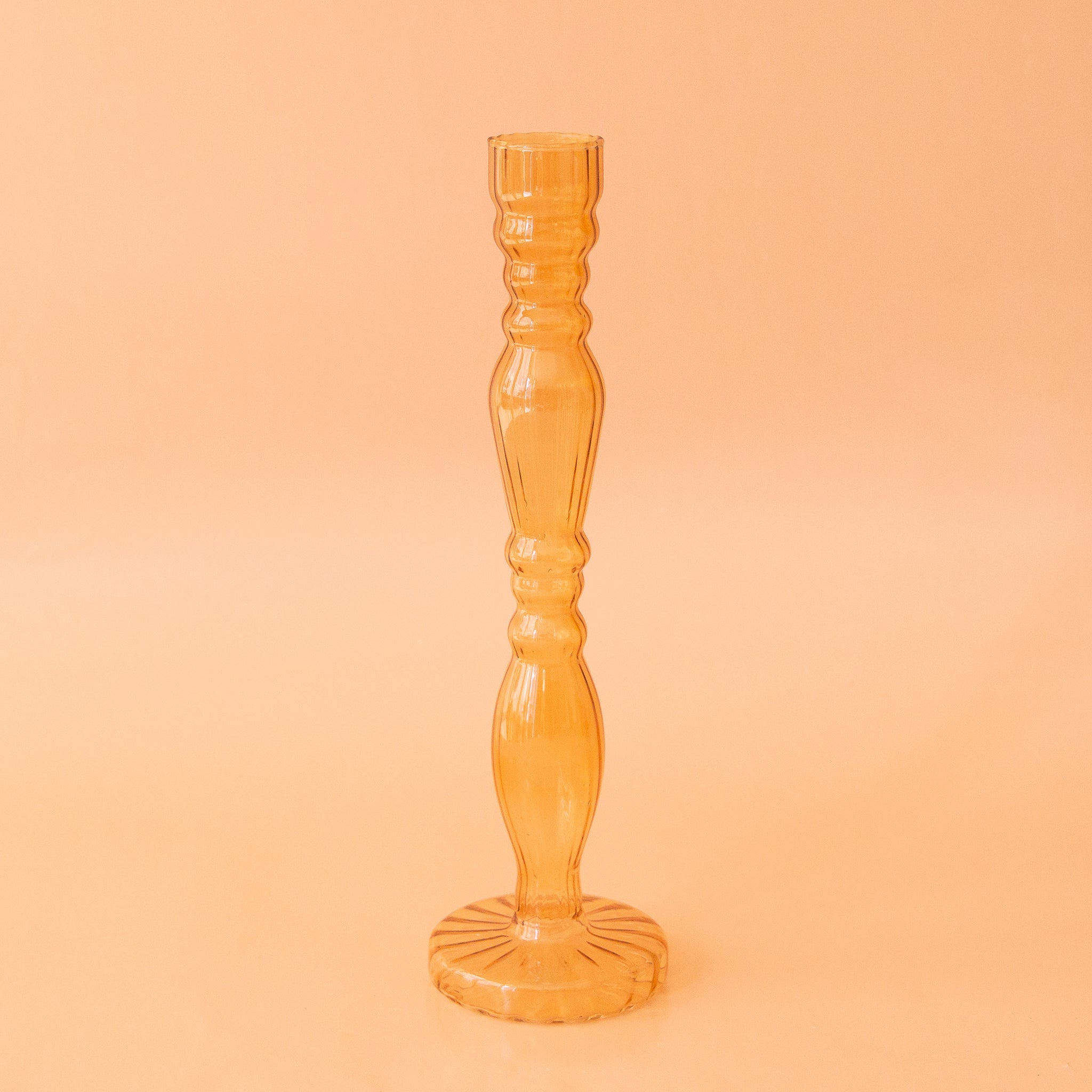 A yellow bud vase with intricate details and made of glass.
