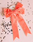 On a light pink background is a peach velvet bow.