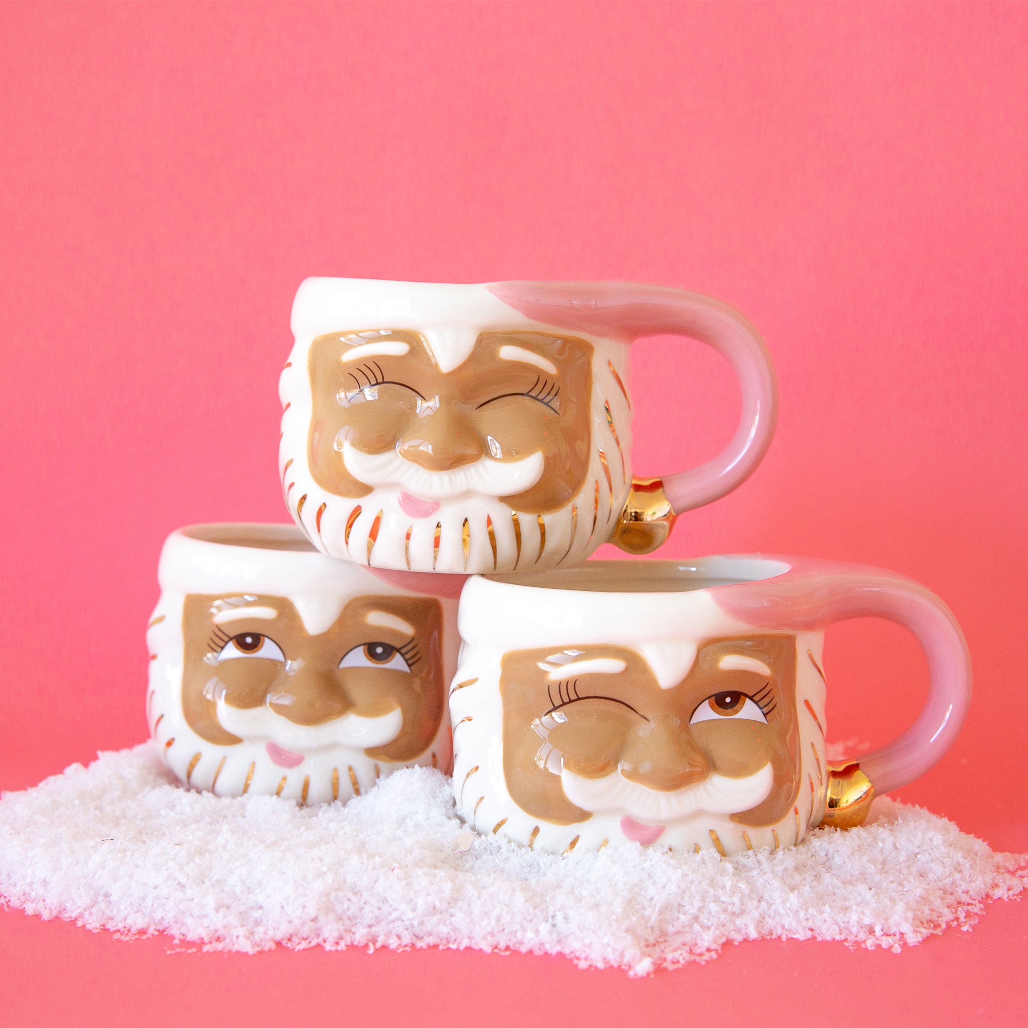 On a pink background is three of the papa noel mugs with different expressions.