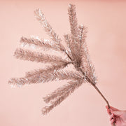 On a pink background is a silver tinsel tree sprig. 