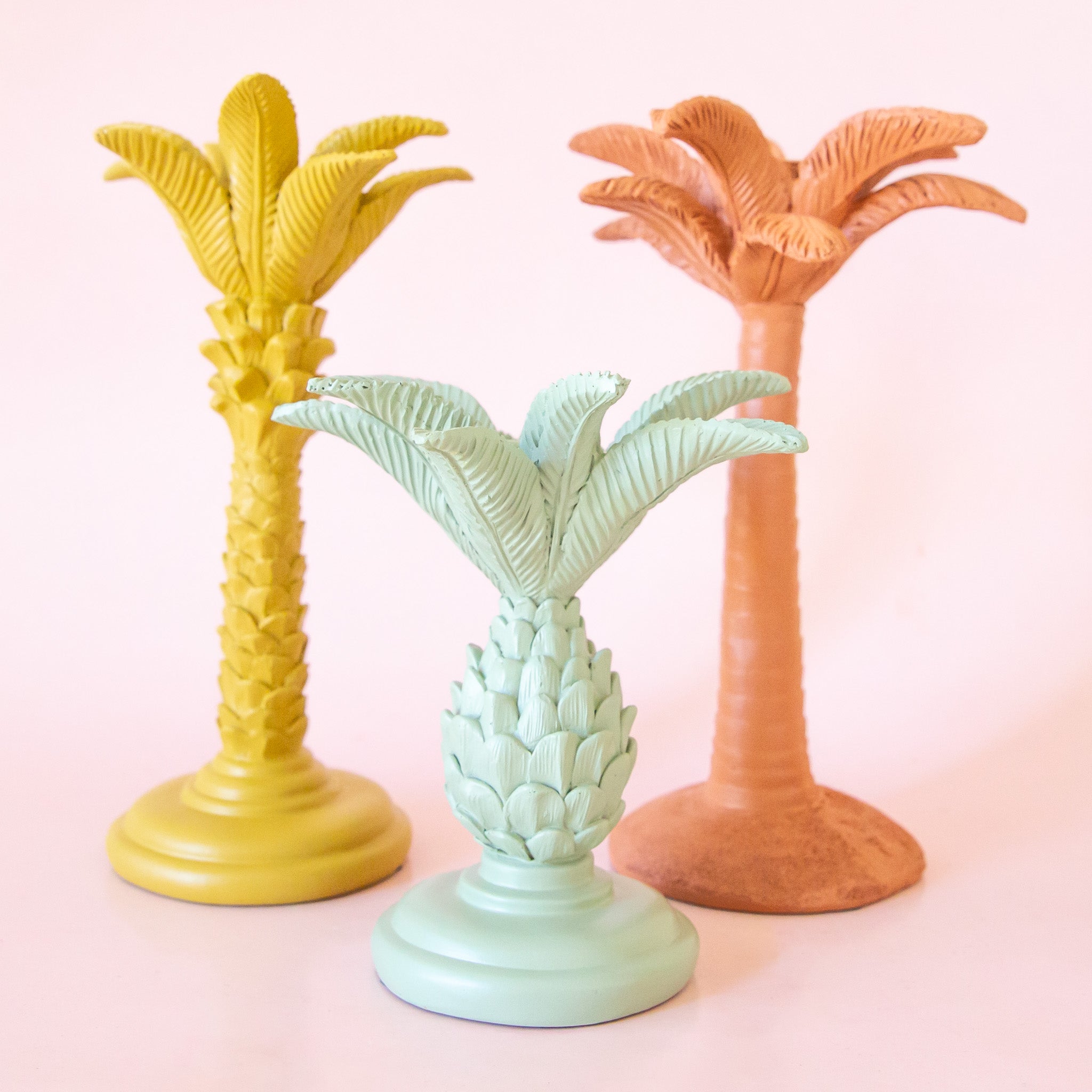 Three pineapple palm tree shaped taper candle holders in mint, yellow and clay. 