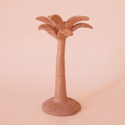 A clay colored palm tree shaped taper candle holder. 