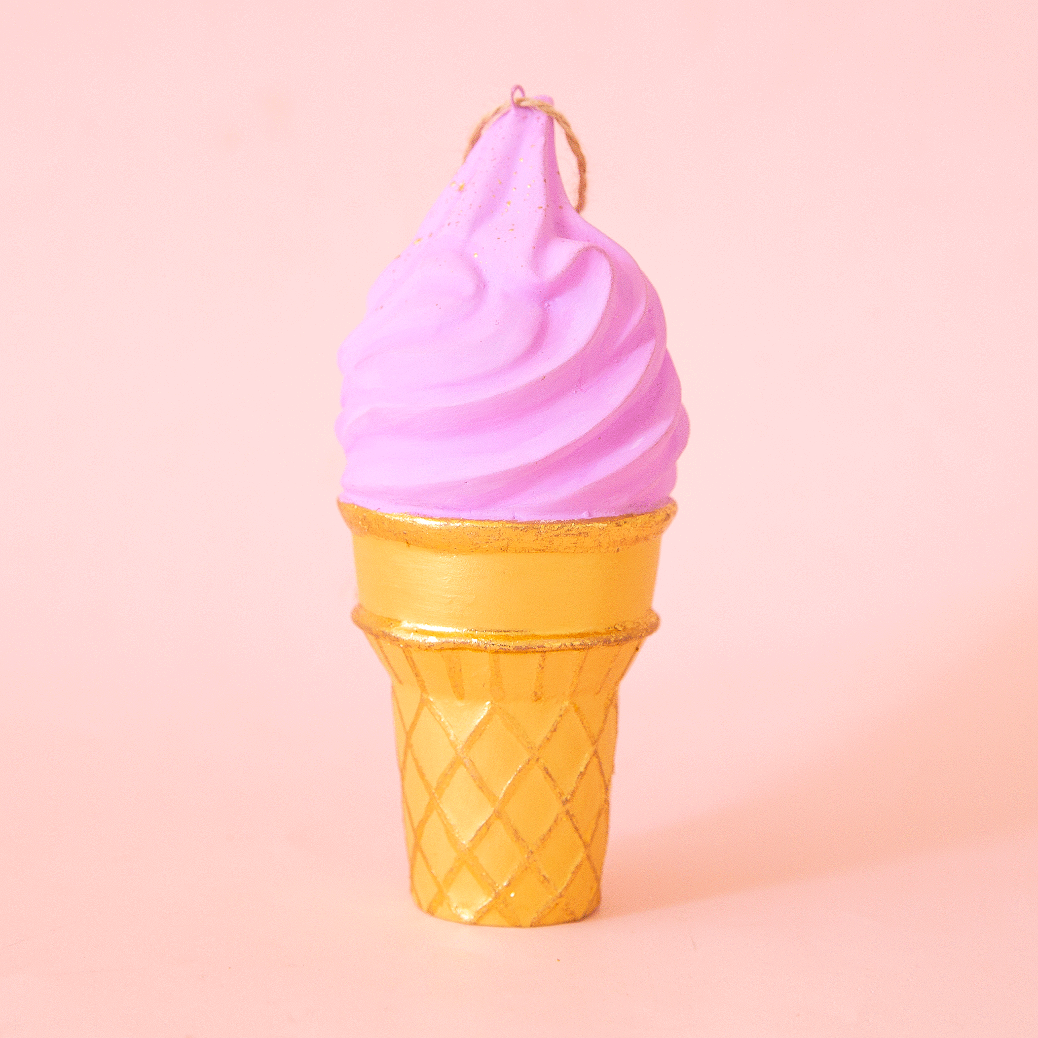 On a pink background is a lavender ice cream cone shaped ornament.