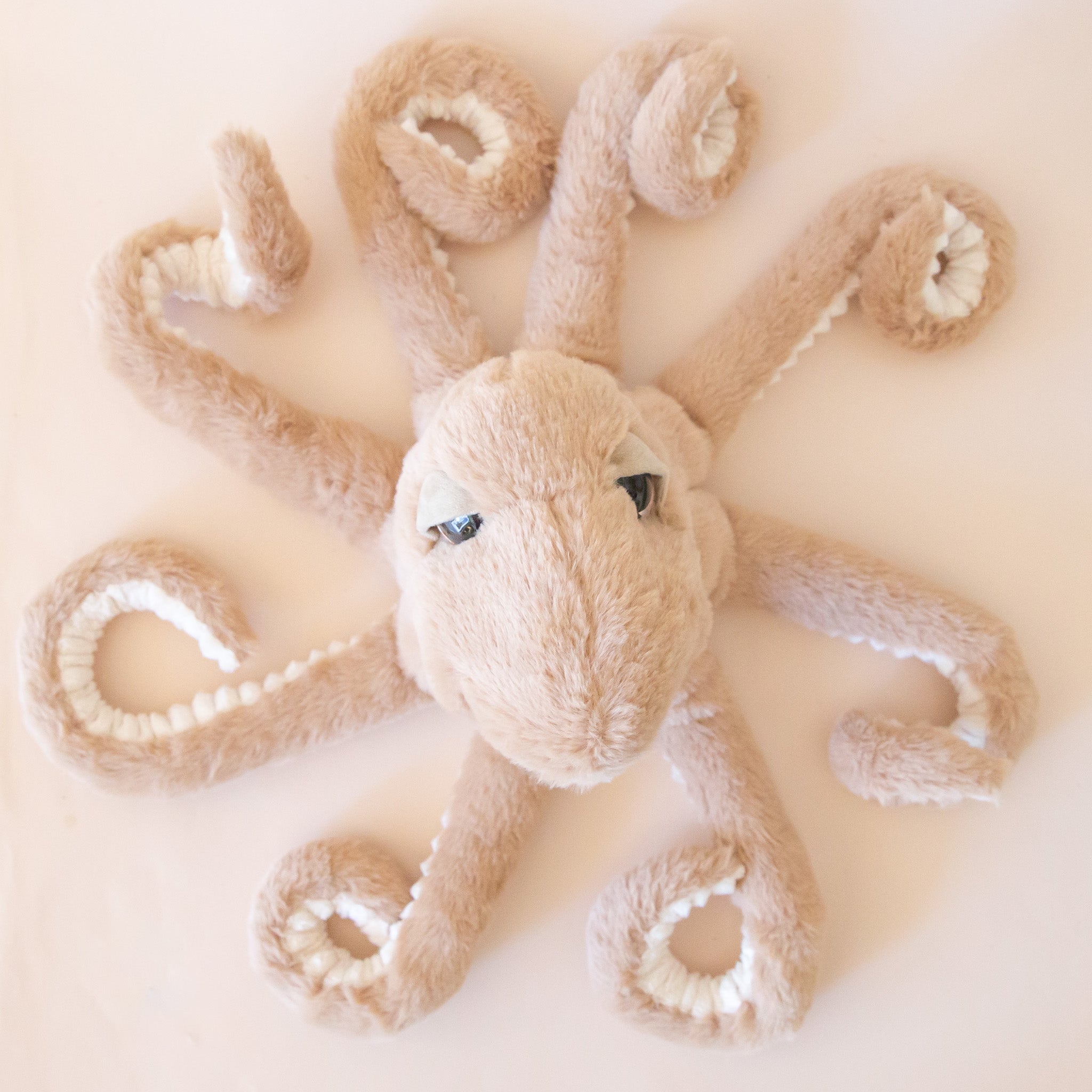 A brown octopus shaped stuffed animal. 