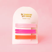 A set of 6 straight bobby pin clips in pink and orange.