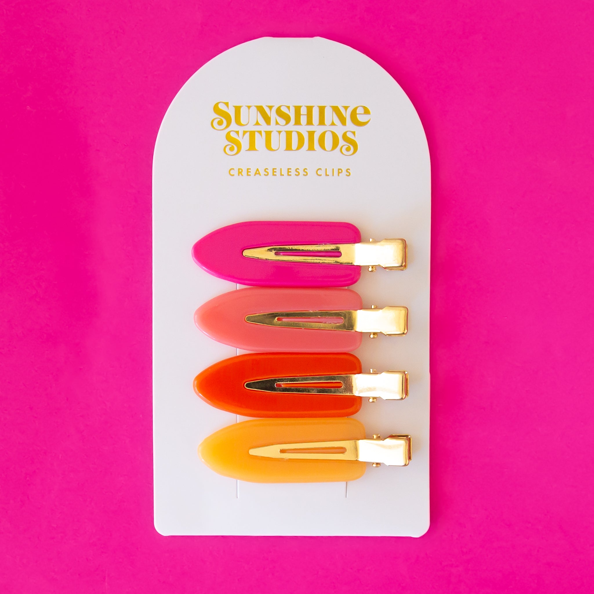 Four vibrant colored creaseless hair clips in orange, pink and yellow shades.