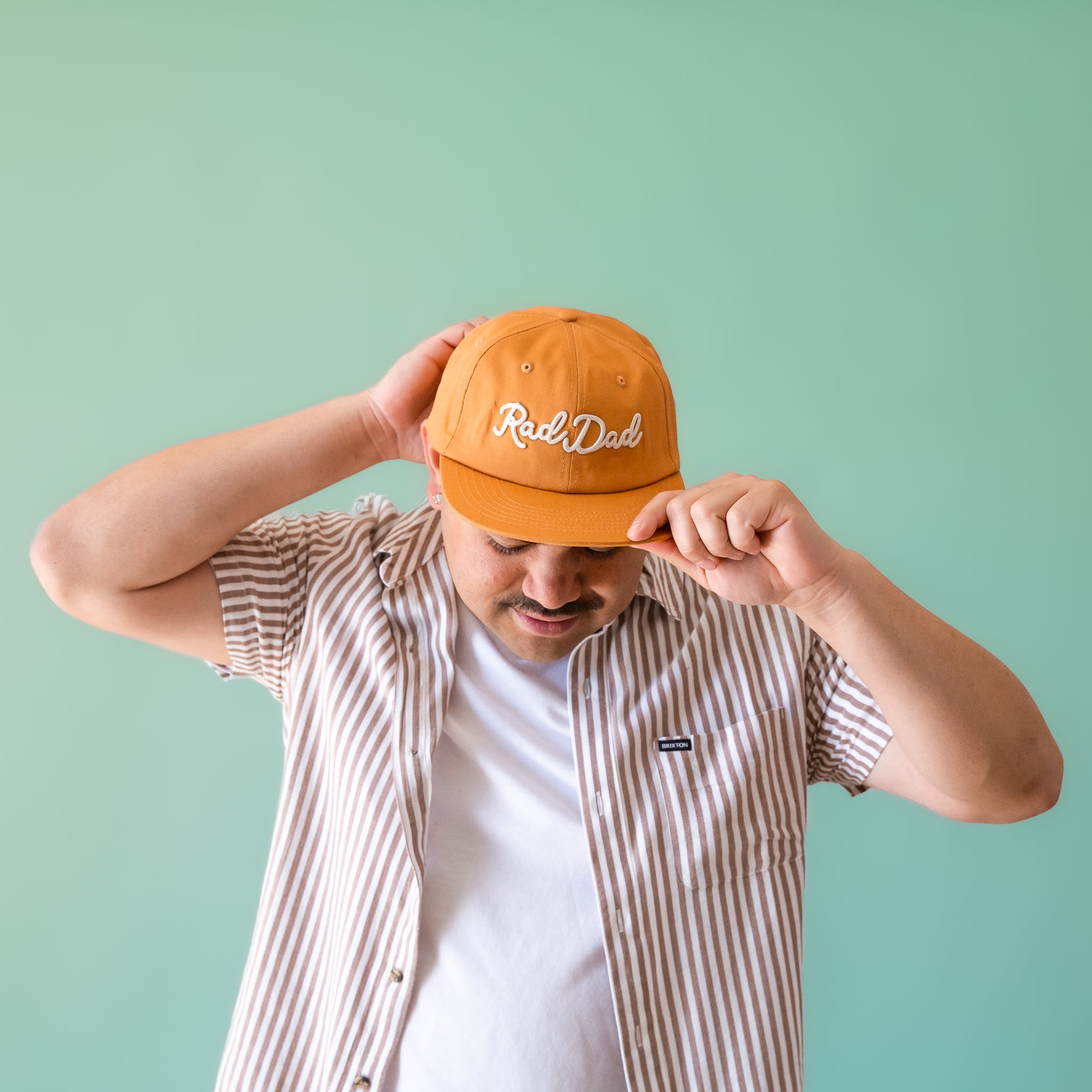 A flat brimmed burnt orange had with white embroidering that reads, &quot;Rad Dad&quot;.