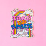 A multi colored sparkle sticker that reads, "Take Up Space" with a colorful rainbow design. 