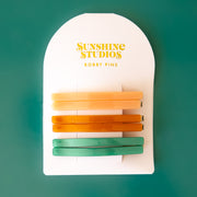 A set of yellow, orange and green bobby pin clips.