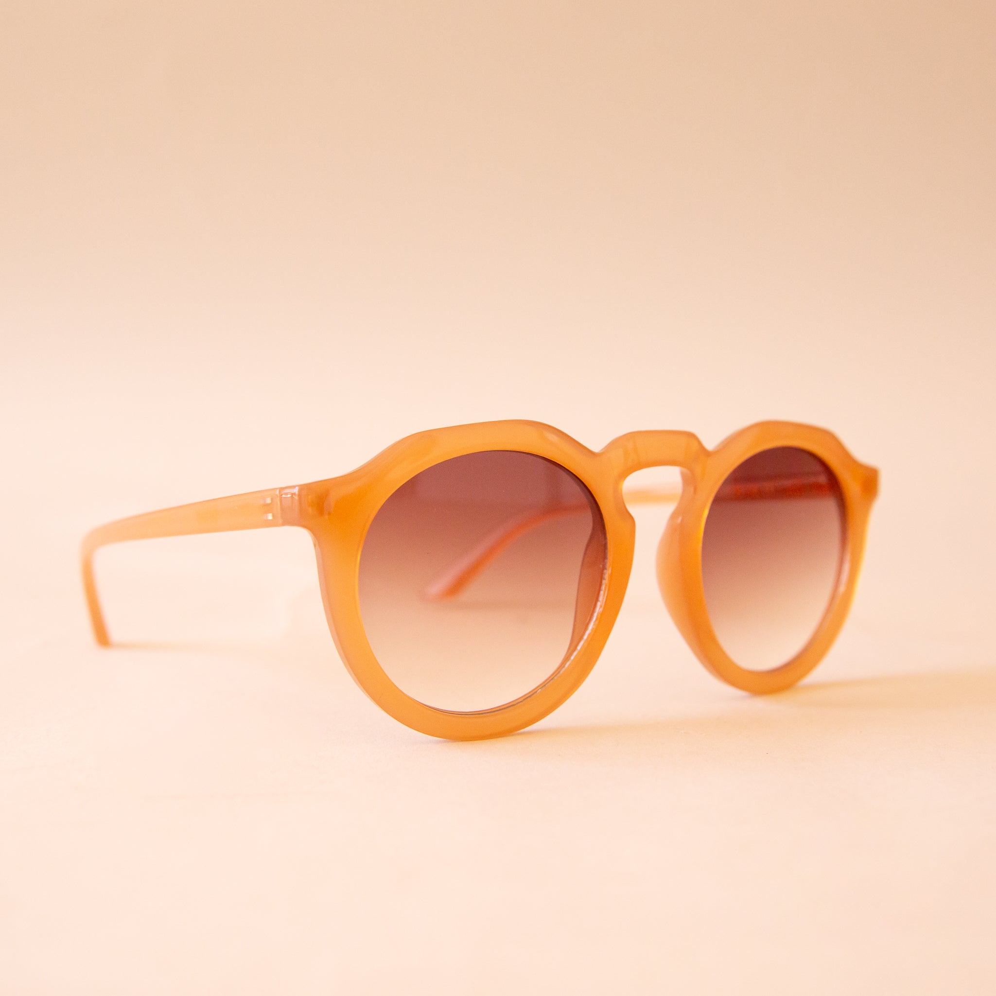 A warm brown pair of round sunglasses with a brown gradient lens.