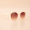 A white pair of rounded sunglasses with a brown lens.