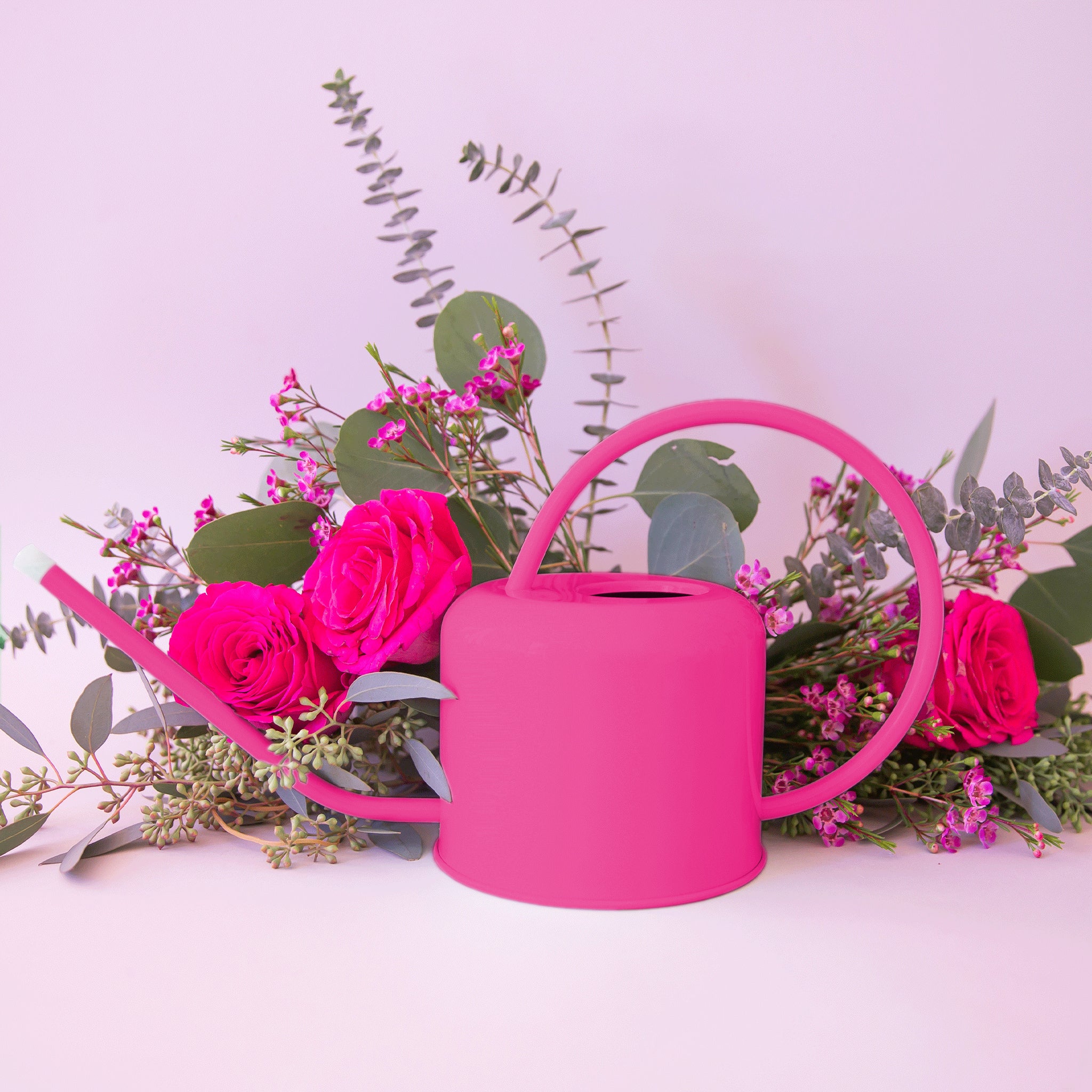 A hot pink metal watering can with a rounded handle and a long spout. 