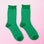 A pair of emerald green crew socks with a lighter green stripe and a ruffle edge at the top. 