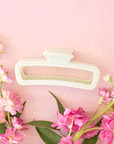 On a pink background is a rounded rectangle hair claw clip in mint green shade.