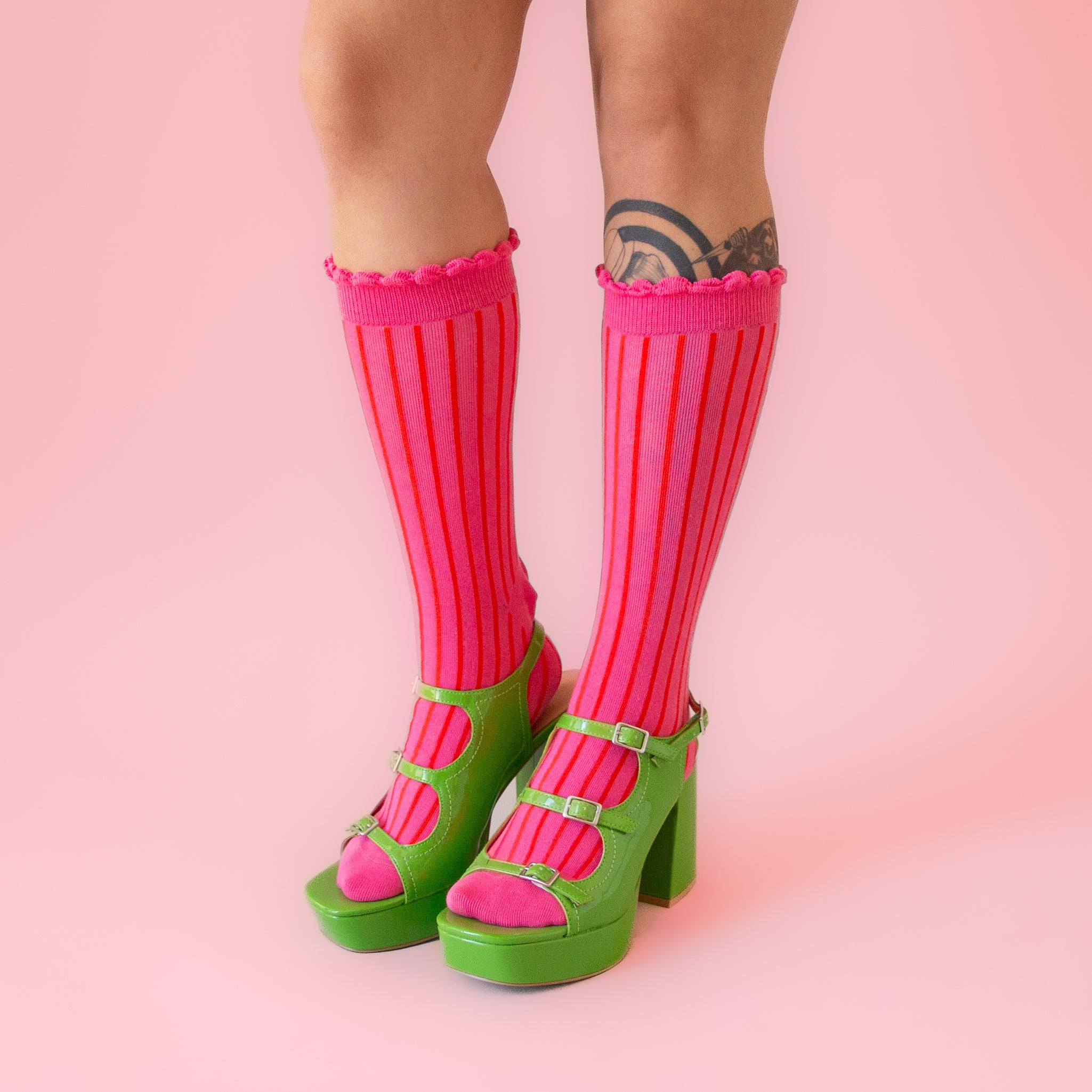 A pair of fuchsia colored striped socks with a ruffle detail at the top. 