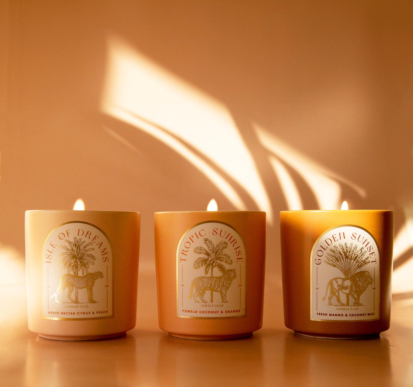 Three different candles with arched labels on them in three different scents. 