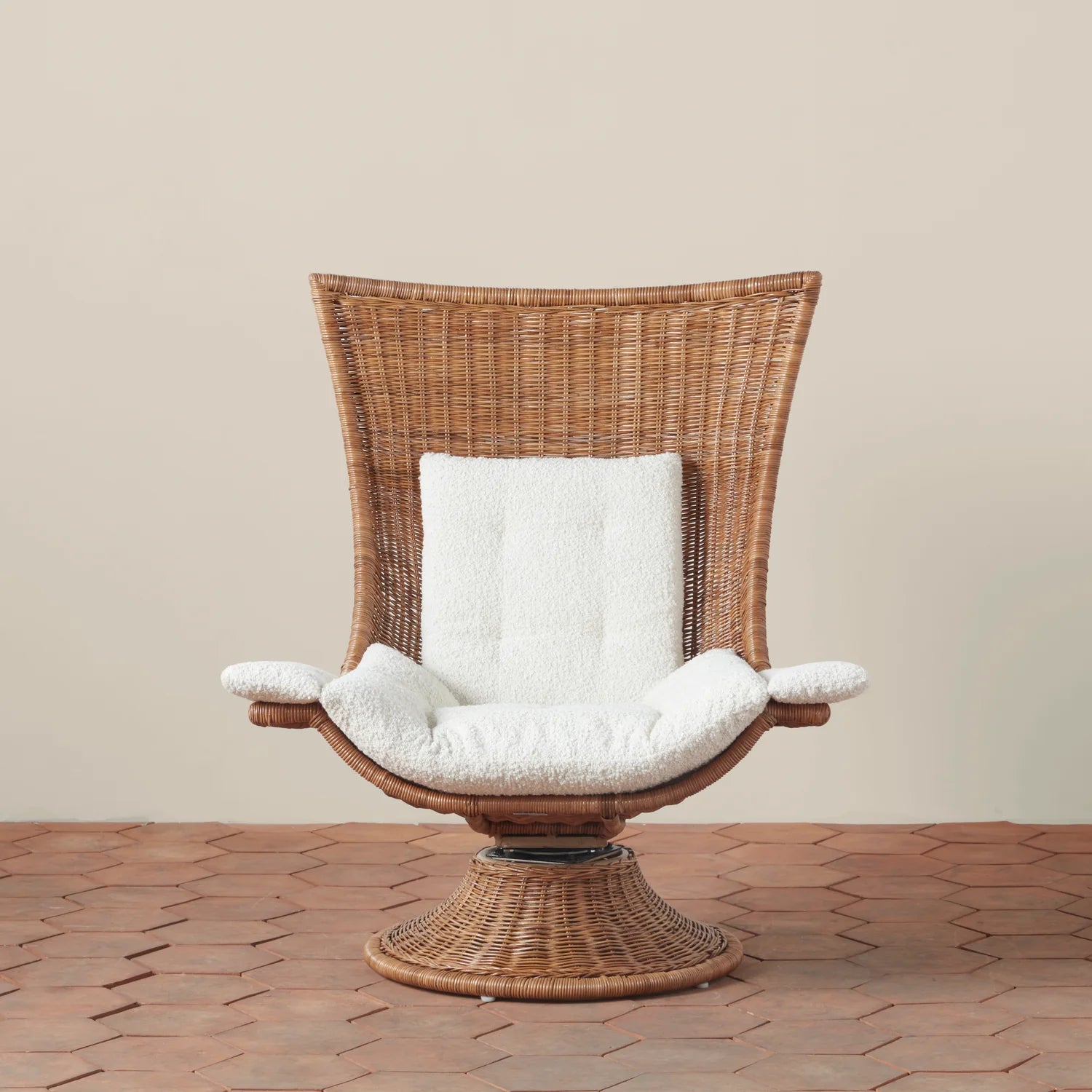 A woven chair with a squared top edge that is curved along the back with an ivory boucle cushion. 