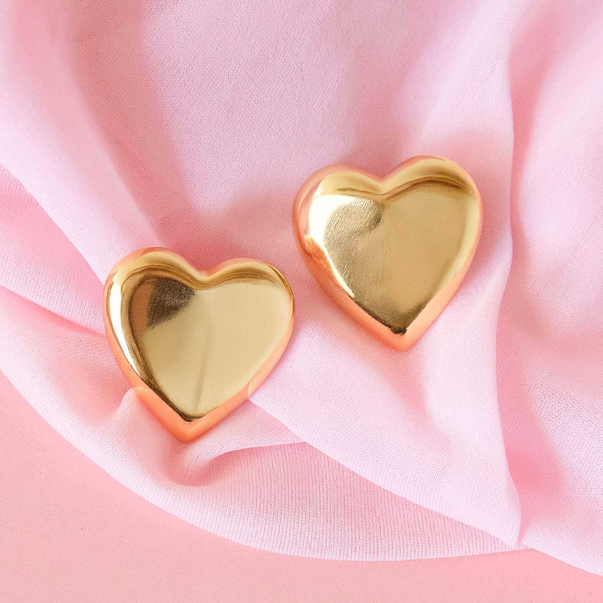 A pair of heart shaped gold earrings. 