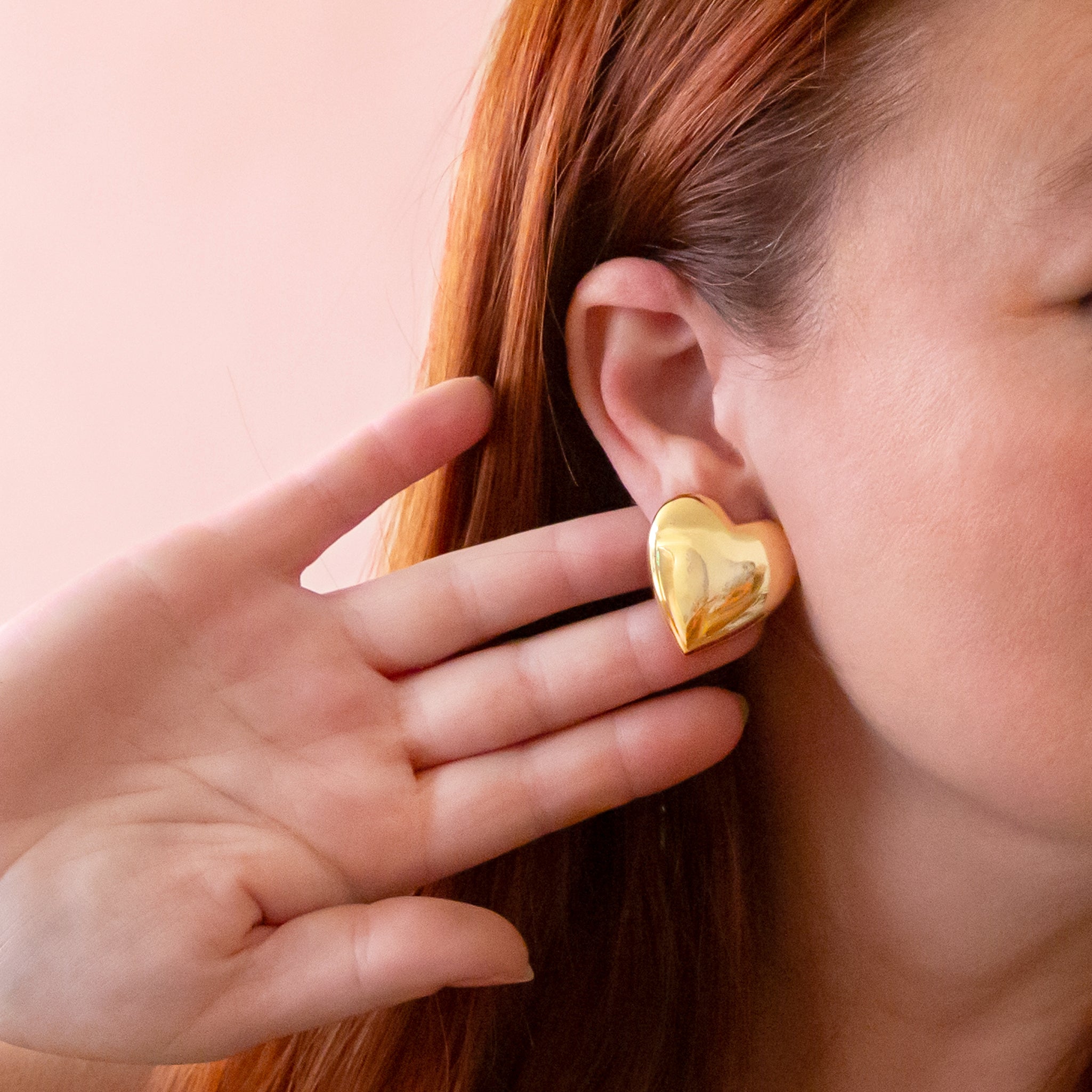 A pair of heart shaped gold earrings. 