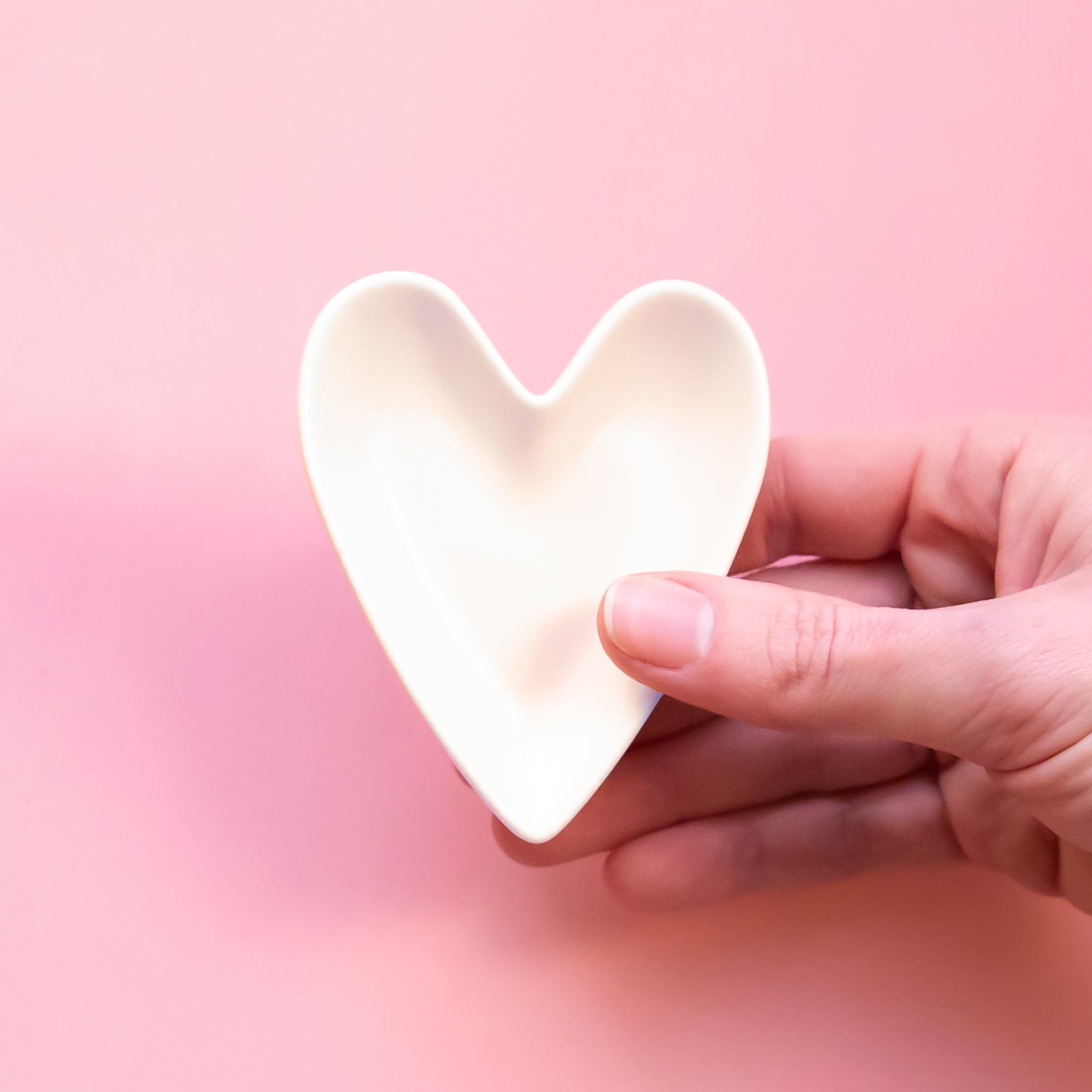 A white, ceramic, heart shaped trinket dish. 