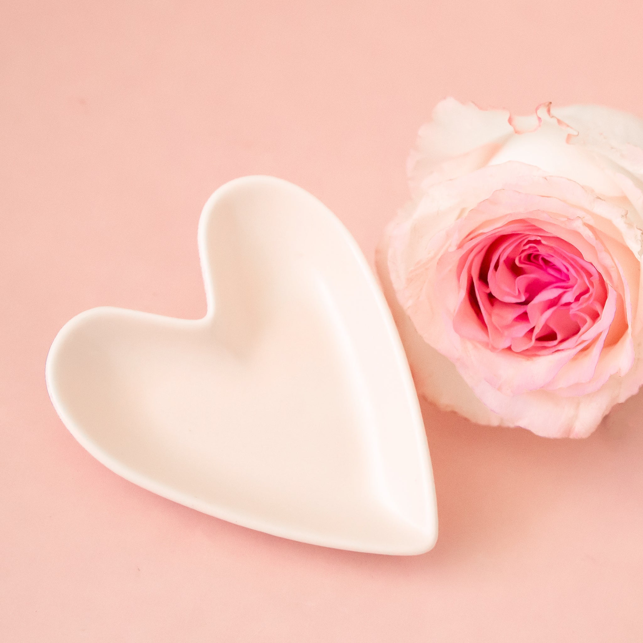 A white, ceramic, heart shaped trinket dish. 