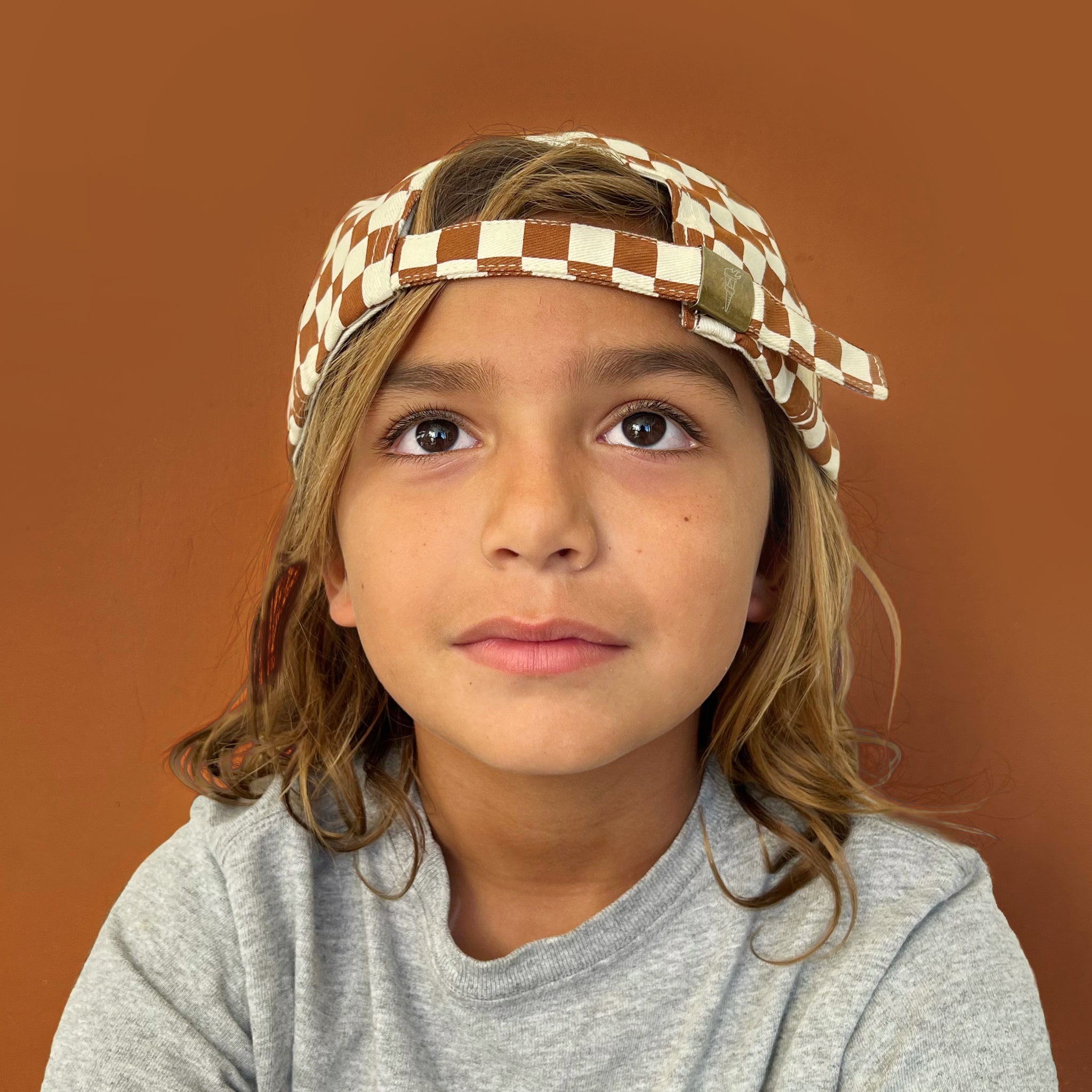 A rust and ivory checker pattern baseball hat for kids. 