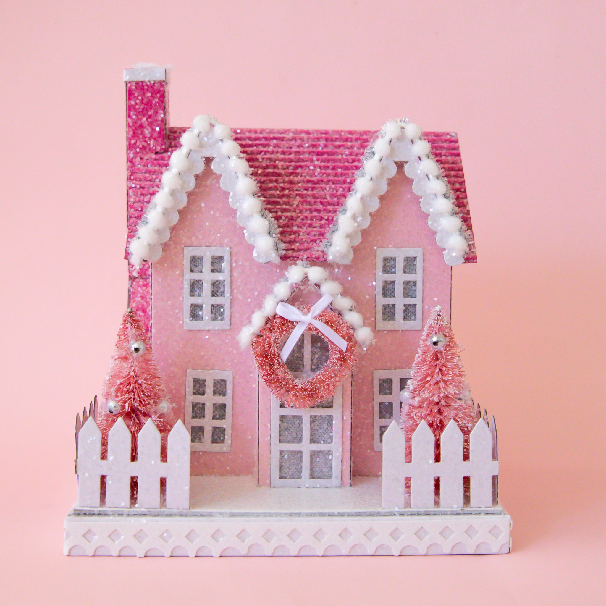 A pink and white holiday decor decorated mini manor shaped house. 