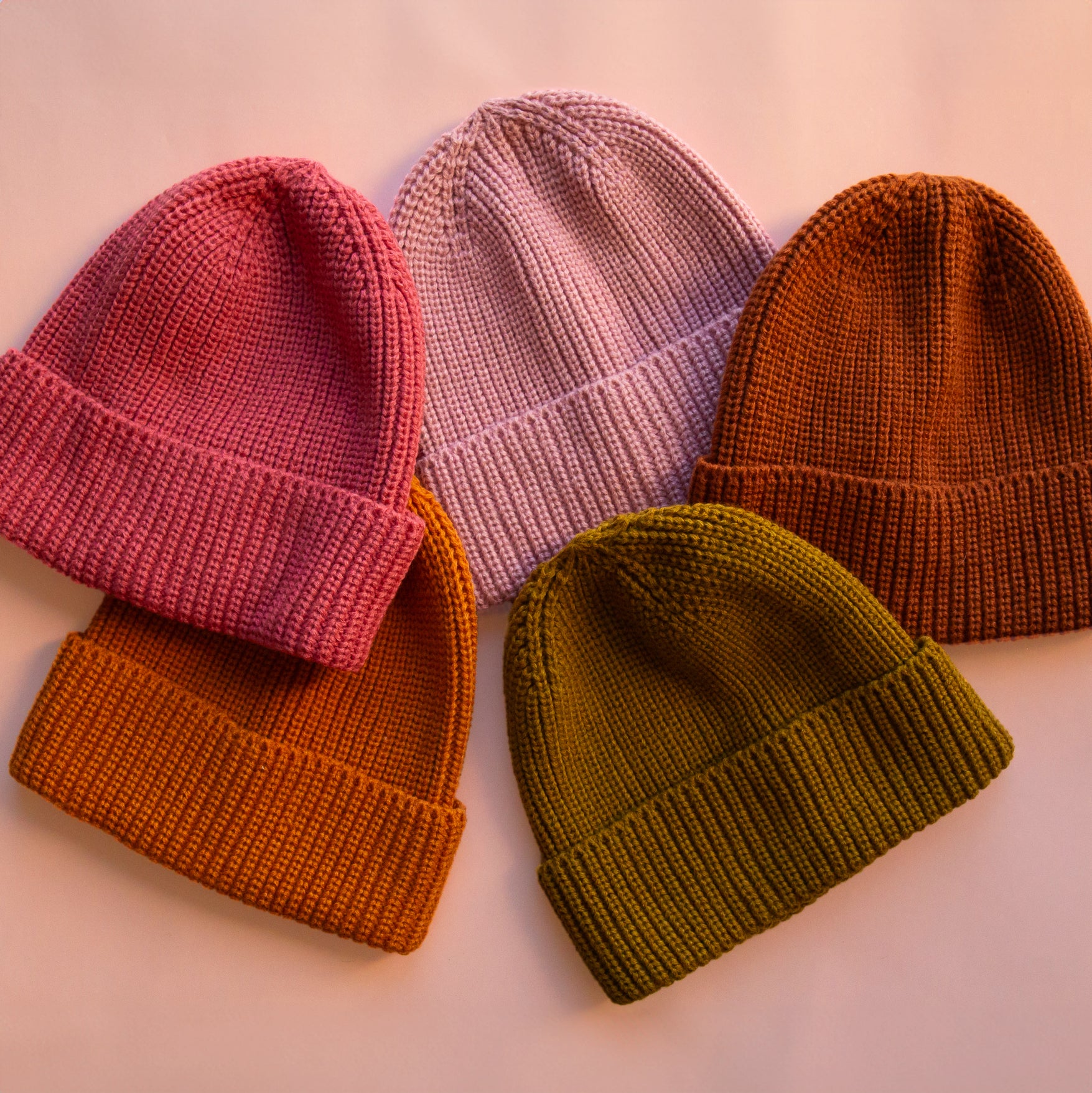 An assortment of five knit beanies in five different colors. 